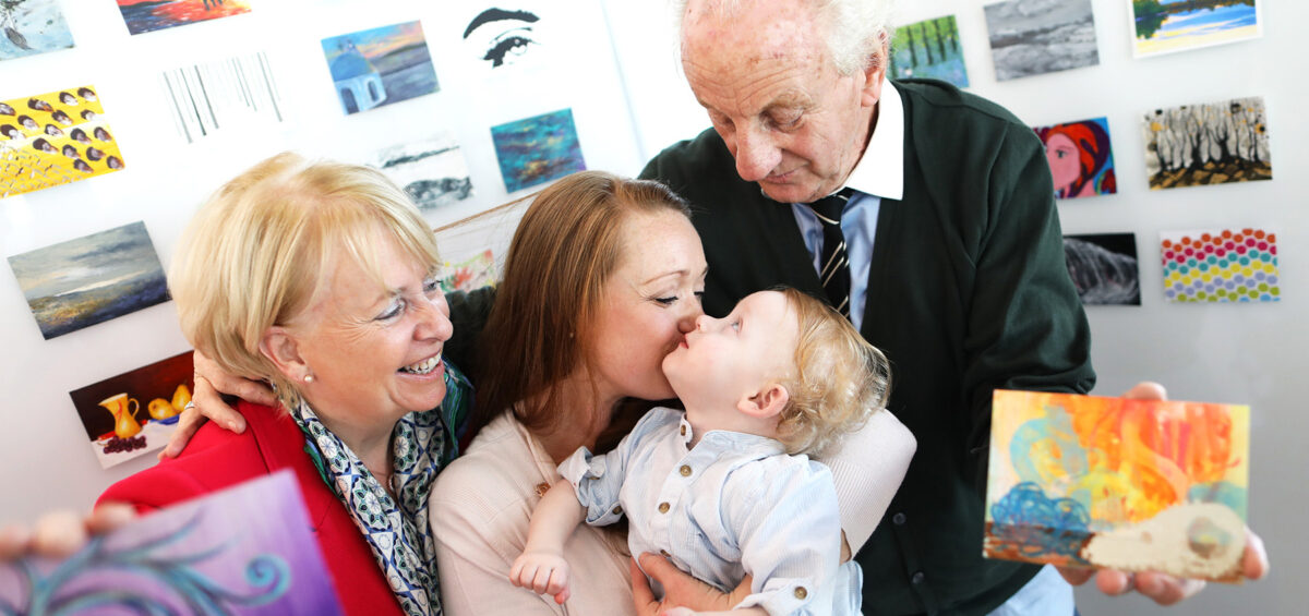 Family smiling and holding artwork