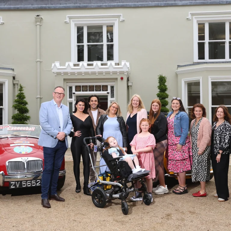 Jack and Jill family, staff, nurse and Jake Carter and Karen Byrne standing in front of retro cars