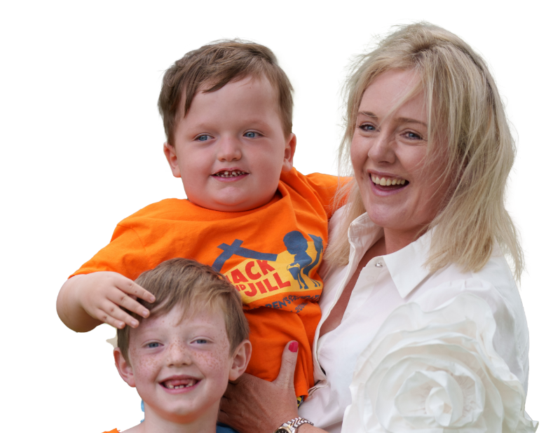 Jack and Jill Criteria for Referrals banner image A smiling blonde woman wearing a white collared shirt holds a young boy wearing a bright orange Jack and Jill Children's Foundation t-shirt. Another young boy with freckles smiles in front of them while the boy being held rests his hand gently on his head. Set against a plain white background."