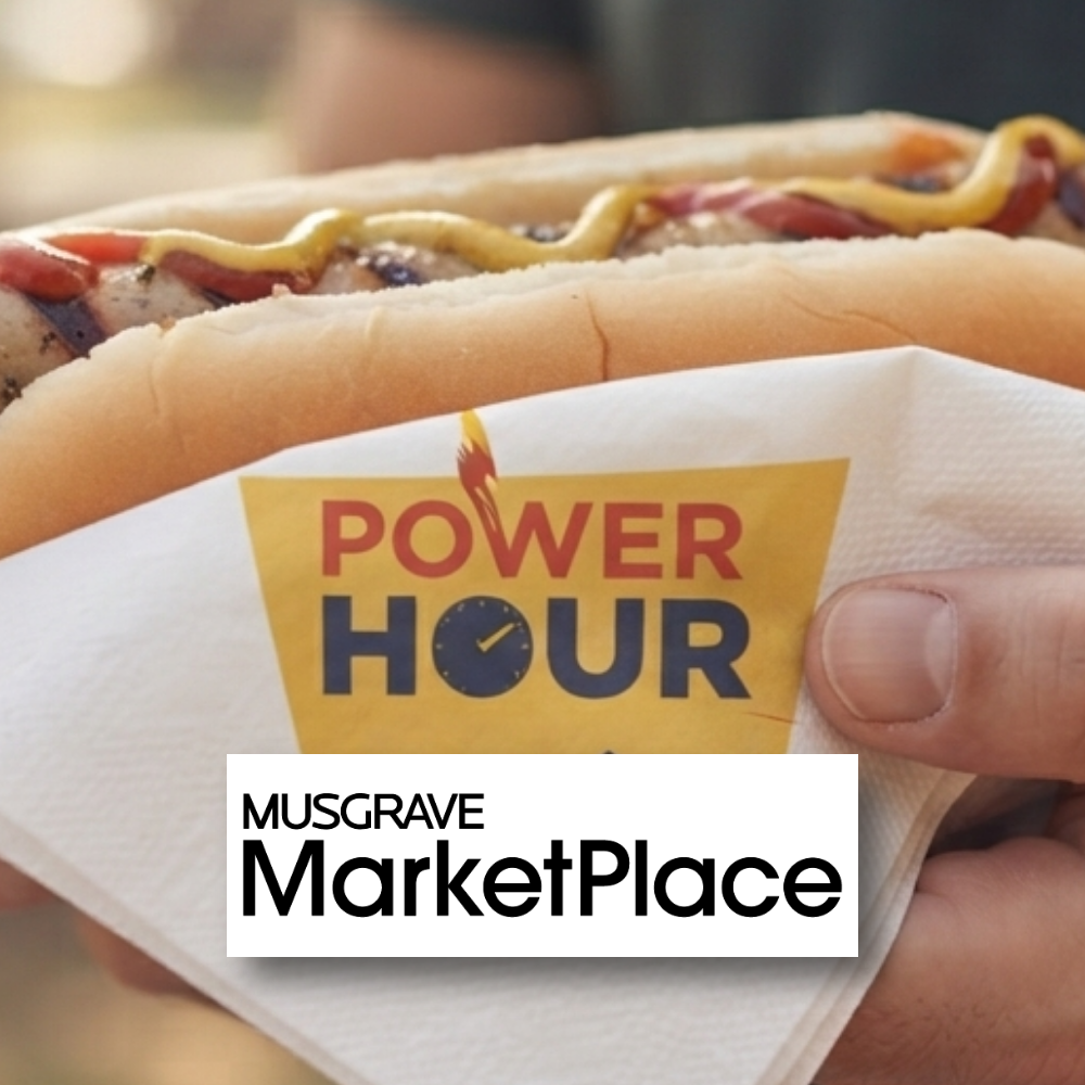 Musgrave Marketplace Sallynoggin BBQ A hot dog with mustard and ketchup held in a napkin featuring a "Power Hour" logo, with the "Musgrave MarketPlace" logo overlaid at the bottom.