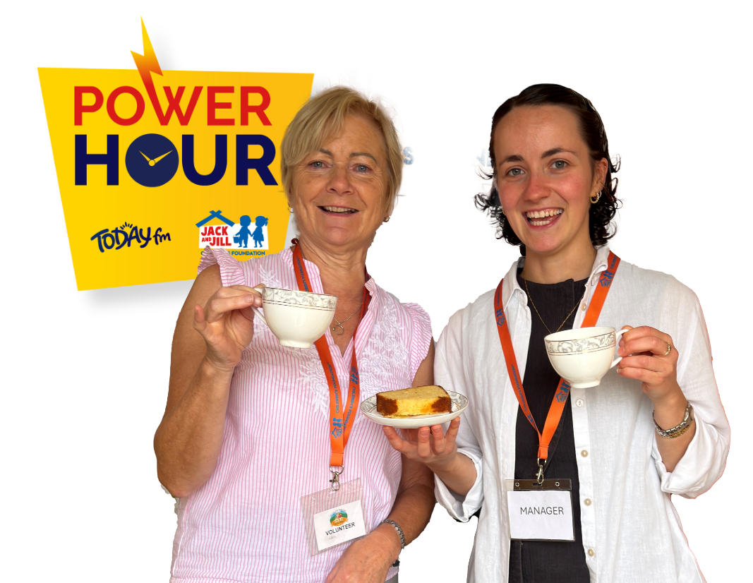 Two smiling women wearing lanyard badges holding teacups and a slice of cake, next to a yellow "Power Hour" logo featuring Today FM and the Jack and Jill Children's Foundation.