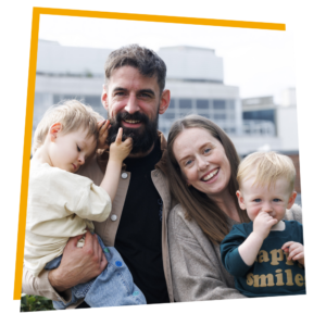 Parents Charlotte and Kevin Ring stand outdoors with their children, Sonaí, 1, and three-year-old Seán Óg—a child supported by the Jack and Jill Children's Foundation
