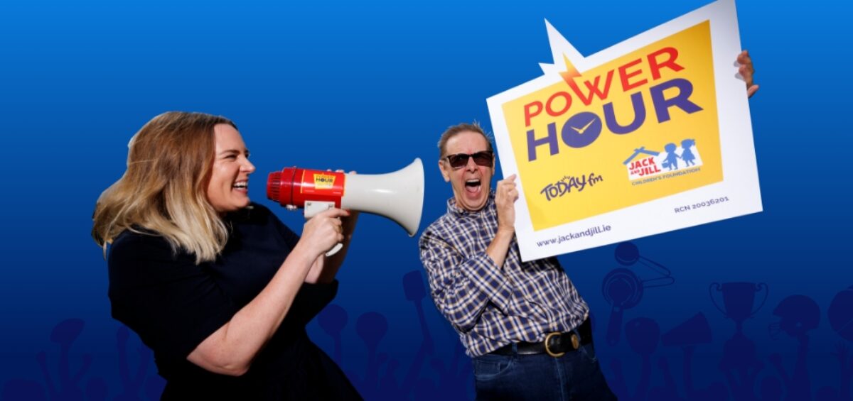 A woman speaking through a megaphone at a man holding a large Power Hour promotional sign for Today FM and the Jack and Jill Children's Foundation.