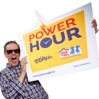 Today FM presenter Ian Dempsey wears sunglasses and a plaid shirt, shouting enthusiastically while holding a large sign promoting the Power Hour for the Jack and Jill Children's Foundation.