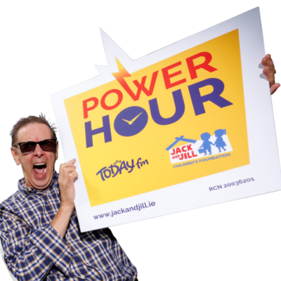 Today FM presenter Ian Dempsey wears sunglasses and a plaid shirt, shouting enthusiastically while holding a large sign promoting the Power Hour for the Jack and Jill Children's Foundation.