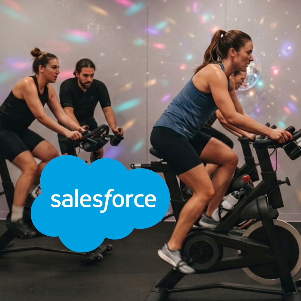 Salesforce Disco Spin People participating in an indoor spin class under colorful disco lighting, with the Salesforce logo overlaid in the foreground.